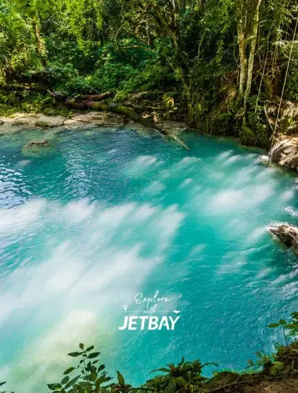 Turquoise blue natural pool surrounded by lush tropical rainforest at Blue Hole, Ocho Rios Jamaica