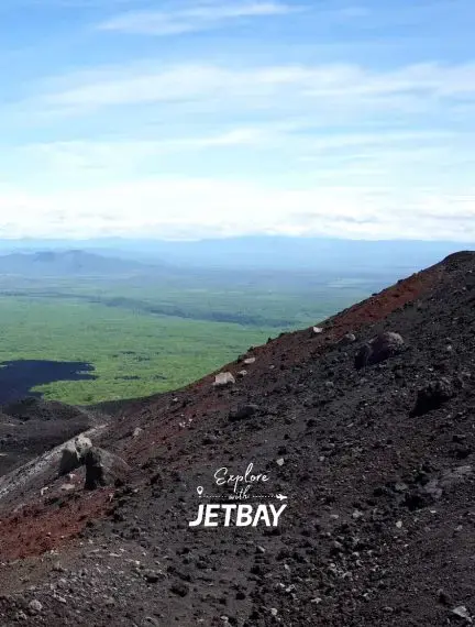 Volcanic black lava slopes of Cerro Negro overlooking León Nicaragua's lush green landscape, a dramatic private charter destination