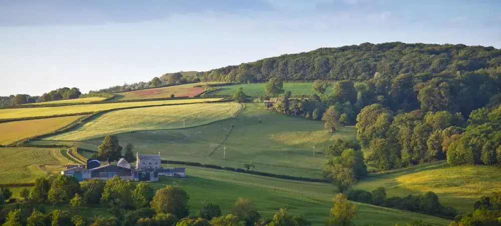 Rolling green hills and patchwork farmland of the Cotswolds countryside, a premier private jet destination in England