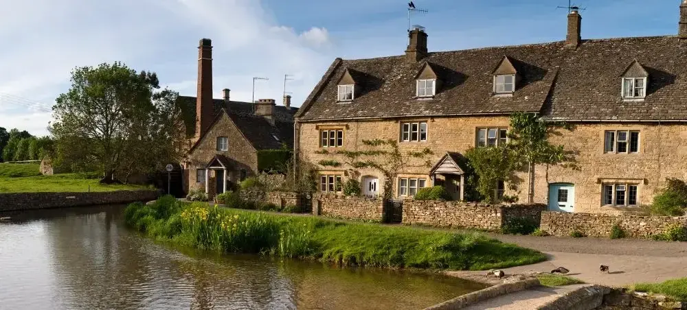 Limestone cottages lining a tranquil river in the Cotswolds, an English destination accessible by private jet charter