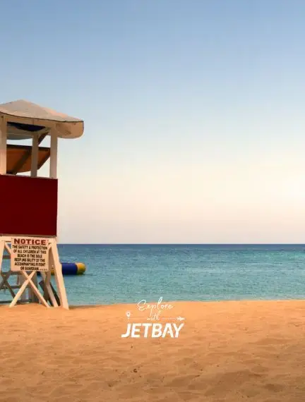 Lifeguard tower on the golden sands of Doctor's Cave Beach in Montego Bay, with calm turquoise Caribbean waters at sunset