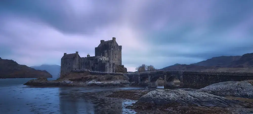 Eilean Donan Castle on a moody loch at dusk, a dramatic Scottish Highlands landmark accessible by private jet charter
