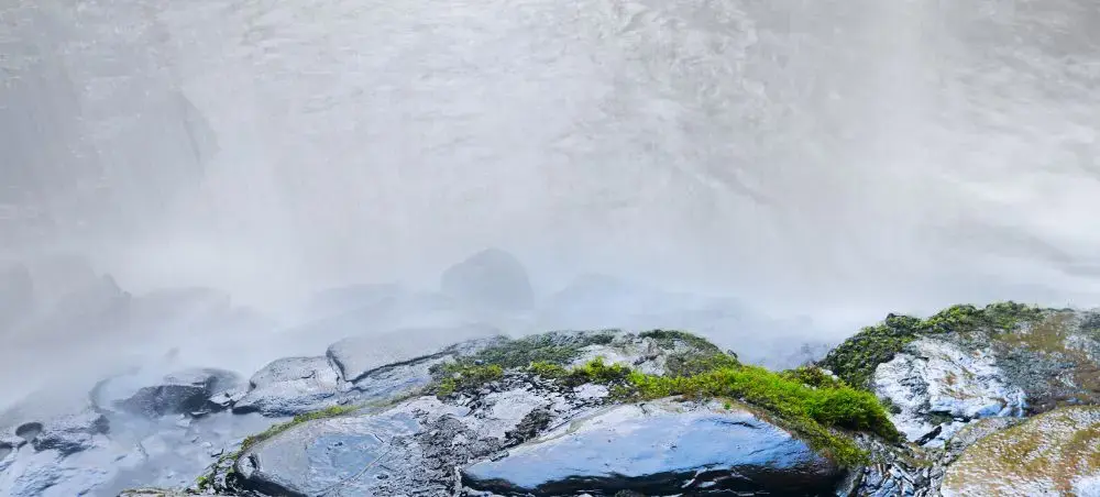 Misty waterfall cascading over moss-covered rocks in Eryri, Snowdonia, a natural landmark via private jet to North Wales
