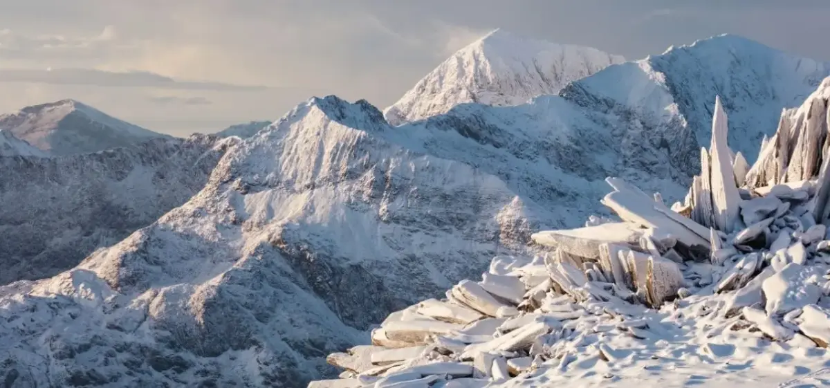 Snow-covered peaks and jagged ice formations in Eryri (Snowdonia), North Wales, a winter landscape accessible by private jet