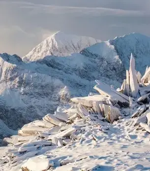 Snow-covered peaks and jagged ice formations in Eryri (Snowdonia), North Wales, a winter landscape accessible by private jet