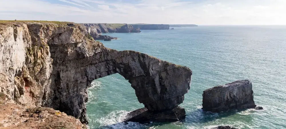 Dramatic Green Bridge of Wales rock arch rising from the Pembrokeshire coast, a landmark accessible via private jet to Wales