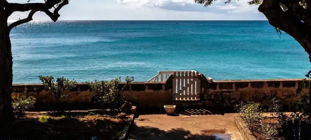 Beachfront garden gate opening to turquoise Caribbean Sea in Holetown, Barbados — a premier private jet destination