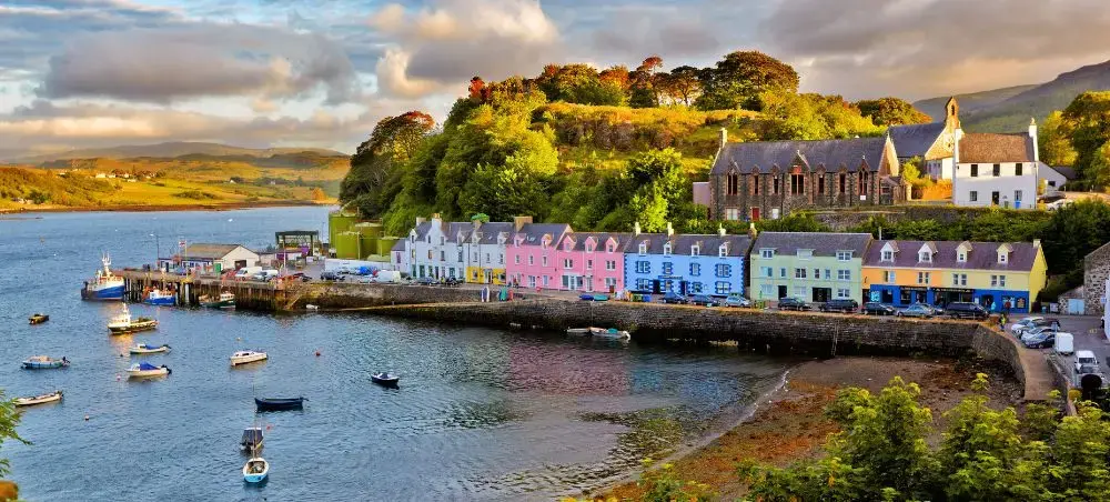Colourful harbour village on the Isle of Skye, Scotland, with moored boats and rolling green hills