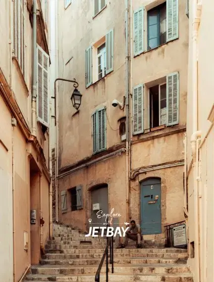 Narrow stone stairway through Le Suquet old town in Cannes, featuring pastel shuttered facades and a vintage lantern
