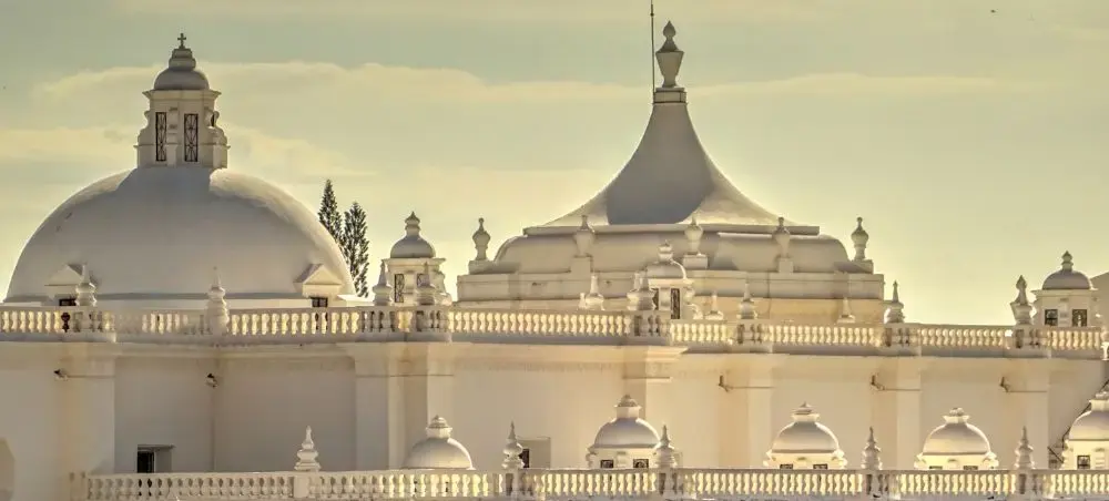 White baroque domes and ornate spires of León Cathedral bathed in golden light, a landmark destination in León, Nicaragua