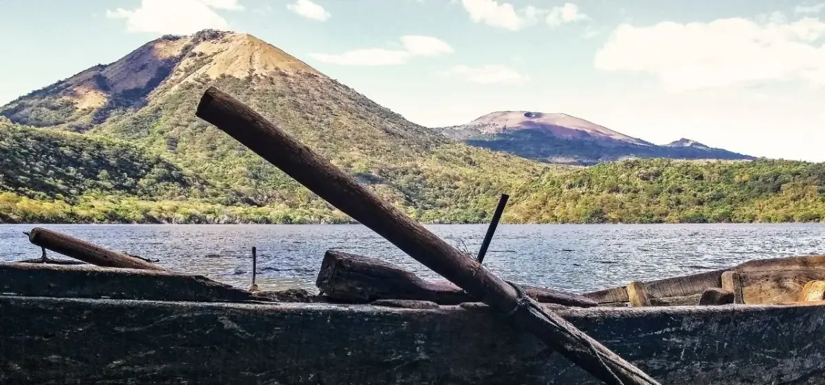 Rustic wooden boat on Lake Xolotlán with twin volcanic peaks of León, Nicaragua rising in the background under a clear sky