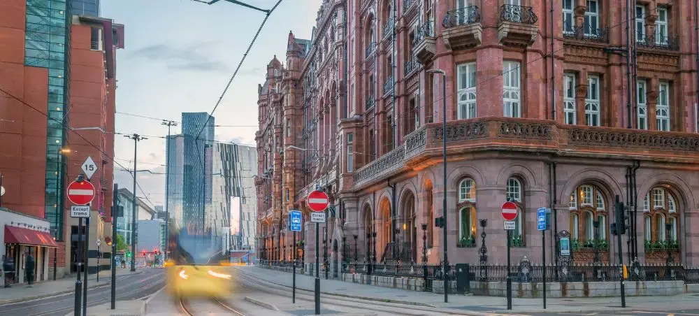 Manchester city centre at dusk with a tram passing the Midland Hotel and skyline, a top private jet destination in the UK