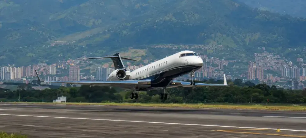 Private jet departing Medellín Colombia with green mountains beyond the runway