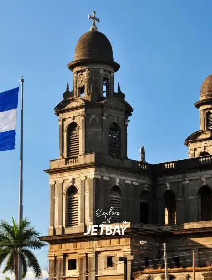 Old Cathedral of Managua bell tower with Nicaraguan flag against clear blue sky, a landmark destination accessible by private jet charter