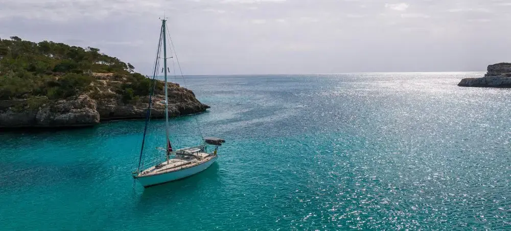 Sailboat anchored in serene Mallorca Cove featuring the blue waters of Spain and the Balearic sea