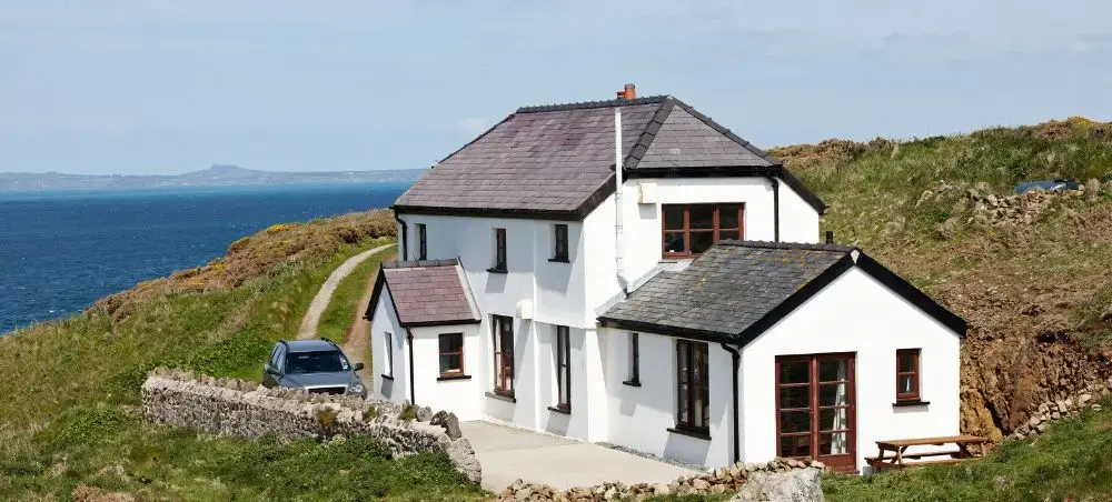 Secluded white coastal cottage perched on Pembrokeshire cliffs overlooking the Irish Sea, accessible by private jet charter