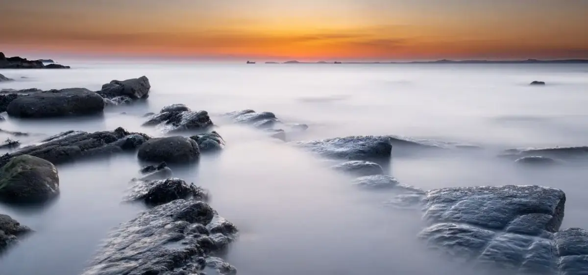 Long-exposure coastal sunset over rocky shores of Pembrokeshire, Wales, a premier destination for private jet travellers