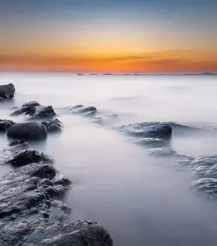 Long-exposure coastal sunset over rocky shores of Pembrokeshire, Wales, a premier destination for private jet travellers