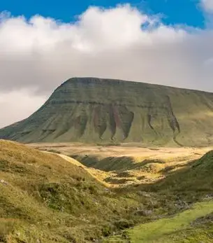 Pen y Fan's distinctive flat-topped summit rising above open moorland in Bannau Brycheiniog, Wales, under a cloudy sky