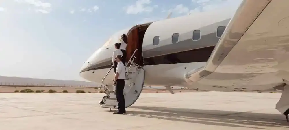 Private jet crew boarding a luxury charter aircraft on a desert tarmac, ready for departure to England
