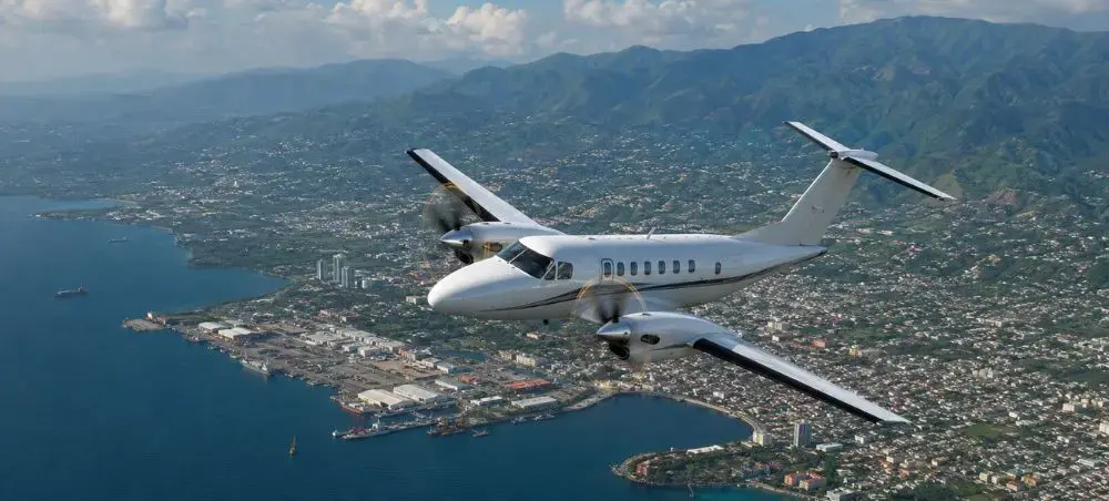 Private jet flying above Kingston, Jamaica with coastline and mountains below