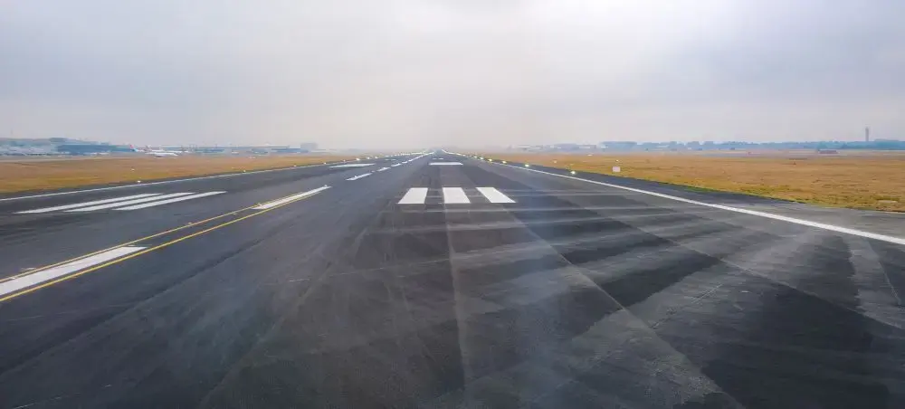 Airport runway ready for private jet departure to Scotland, with runway lights and commercial terminals visible