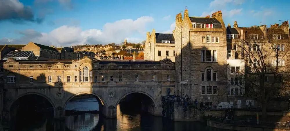 Pulteney Bridge spanning the River Avon in Bath, England, showcasing Georgian limestone architecture and the city's skyline