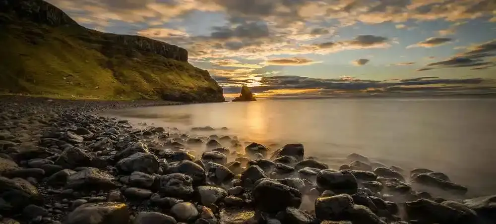 Golden sunset over a Scottish coastal cliff and rocky shoreline, a premier private jet destination in the United Kingdom