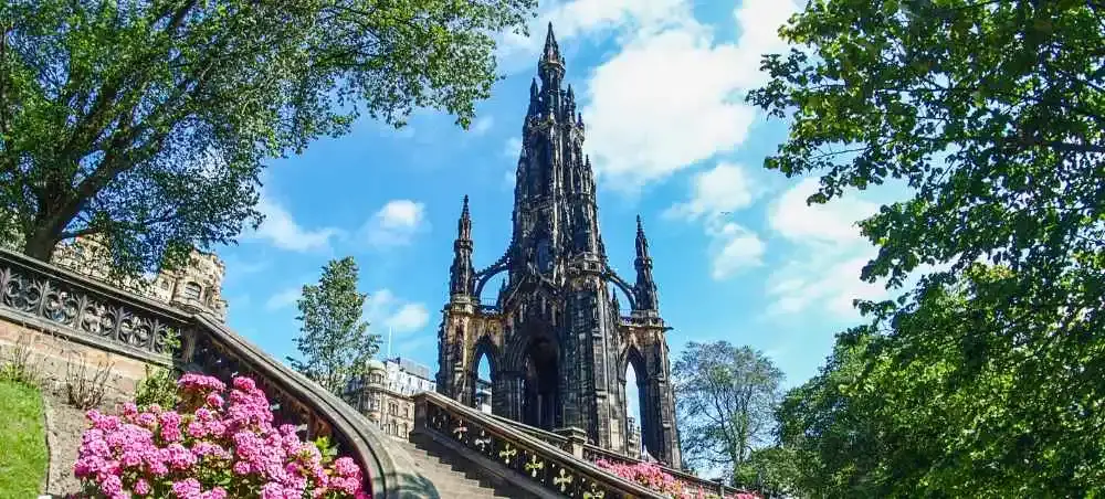 Scott Monument in Edinburgh rising above pink hydrangeas and stone steps on a sunny day, a landmark destination accessible by private jet charter to Scotland