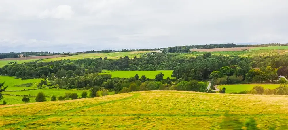 Sweeping aerial view of the Scottish Highlands countryside in Inverness, dense woodland, and rolling hills