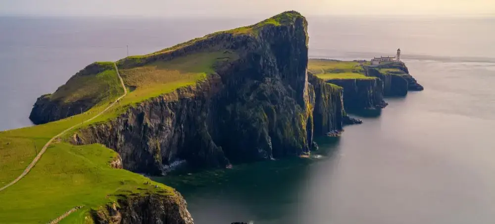 Dramatic aerial view of Neist Point lighthouse perched on rugged Scottish Highland cliffs