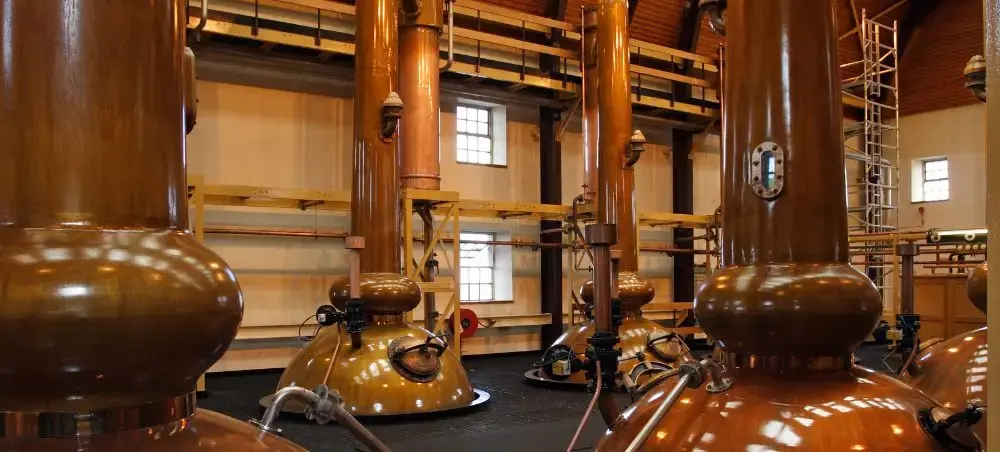 Copper pot stills inside a traditional Scottish whisky distillery, a Highland experience accessible by private jet charter