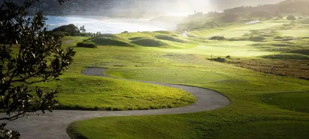 Scenic Welsh with winding path, lush green fairways and misty shoreline
