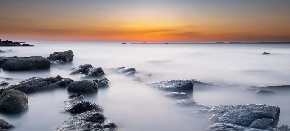Long-exposure sunset over a rocky Welsh coastline in Pembrokeshire, a popular destination for private jet travellers to Wales