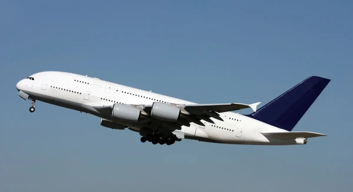 White Airbus A380 wide-body aircraft climbing after takeoff against a clear blue sky
