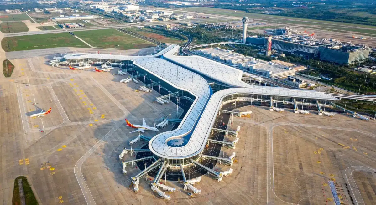 Aerial view of modern Haikou Meilan Airport terminal with curved architecture and control tower in China