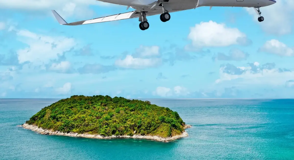 Private jet on final approach over a lush tropical island surrounded by turquoise waters, embodying Jetbay's resort partnership luxury travel experience