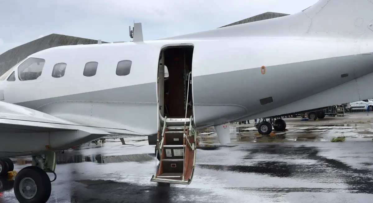 Private jet airstair door open on wet tarmac, ready for boarding — reflecting rising ultra-high-net-worth private aviation demand