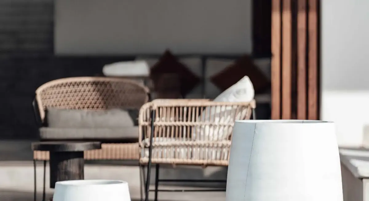 Elegant outdoor lounge seating with woven rattan chairs and neutral cushions in a refined ultra-luxury open-air terrace setting