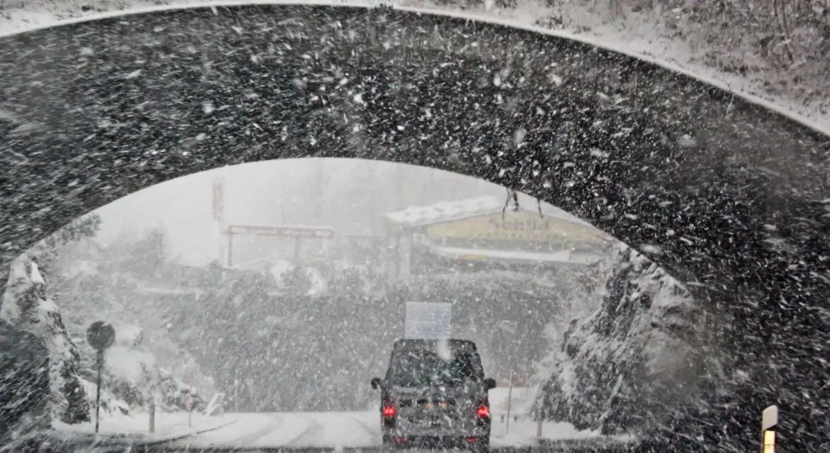 Luxury SUV driving through a blizzard under a stone arch bridge